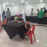 Sepasang adik-beradik menikmati hidangan di Majlis Sambutan Hari Raya Aidilfitri 1446H.