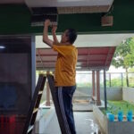 Seorang jemaah sedang membersihkan penapis penghawa dingin.