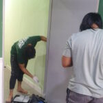 Peserta gotong-royong mengecat pintu surau.