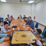 Tetamu majlis 'Open House' Aidilfitri 1445 Hijrah, menjamu selera sambil bermain karom.