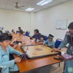 Tetamu majlis 'Open House' Aidilfitri 1445 Hijrah, menjamu selera sambil bermain karom.